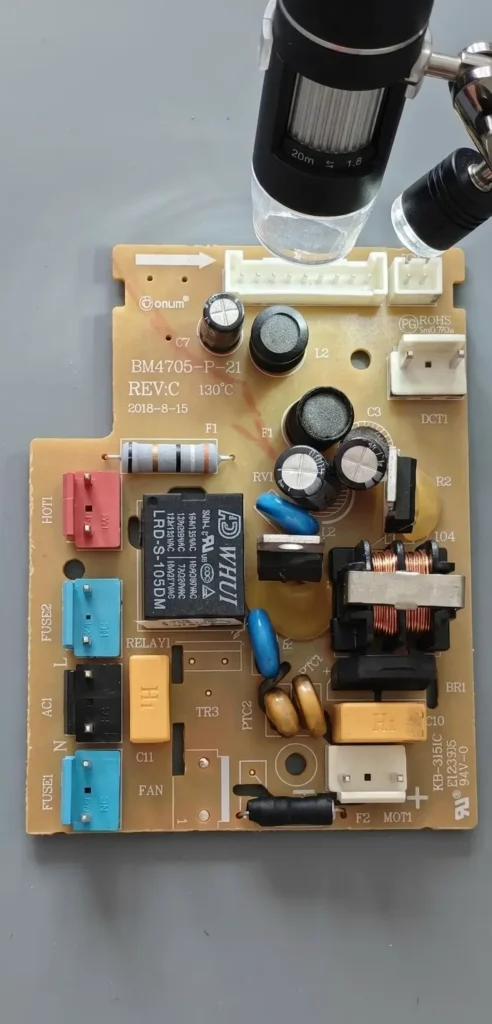 Stereo microscope inspecting the top side of Donlim bread maker power board BM4705-P-21.